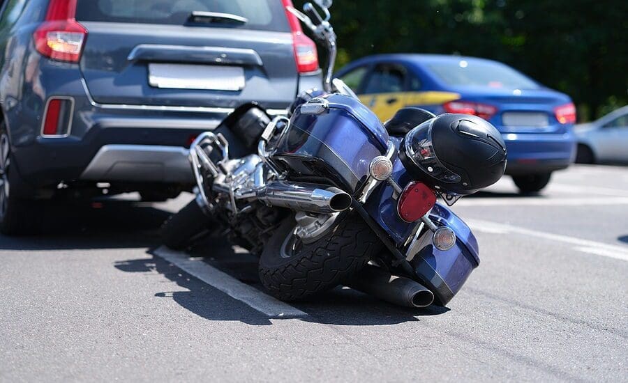 Blue motorcycle lying on road near car closeup