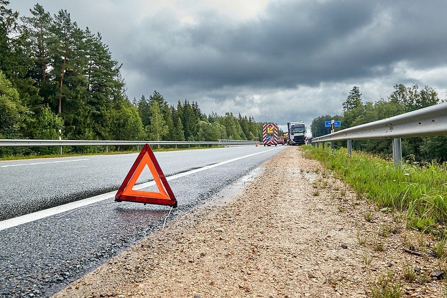 caution sign in the road warns drivers to avoid a truck accident scene in case of danger