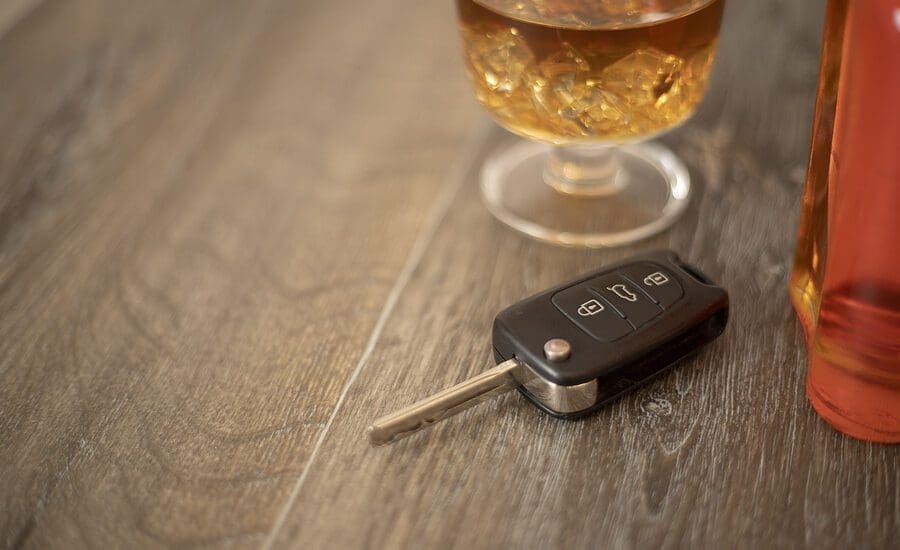 Drunk driving concept - car keys in the foreground with glass of whiskey