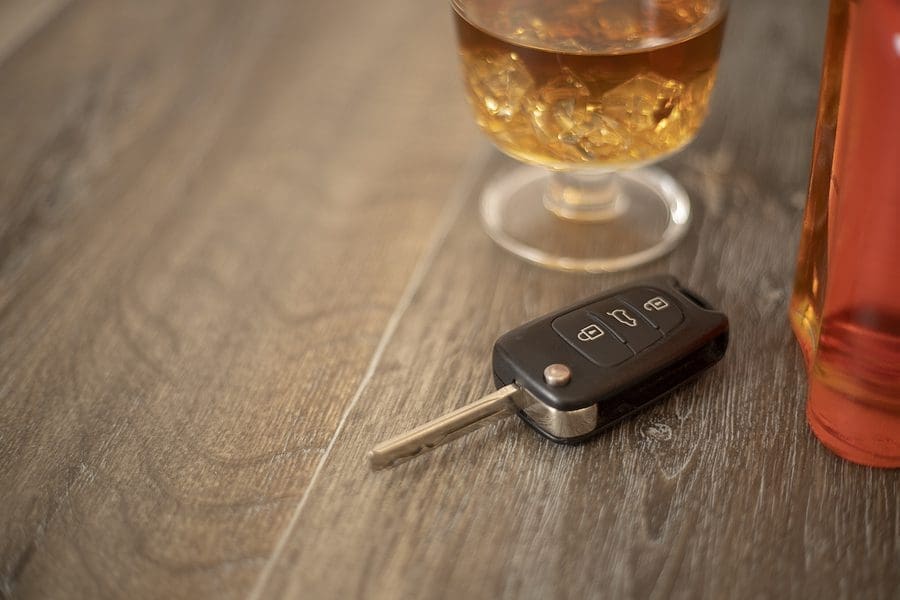 Drunk driving concept - car keys in the foreground with glass of whiskey