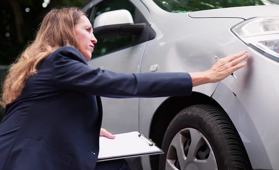 Insurance Agent Inspecting Damaged Car With Insurance Claim Form