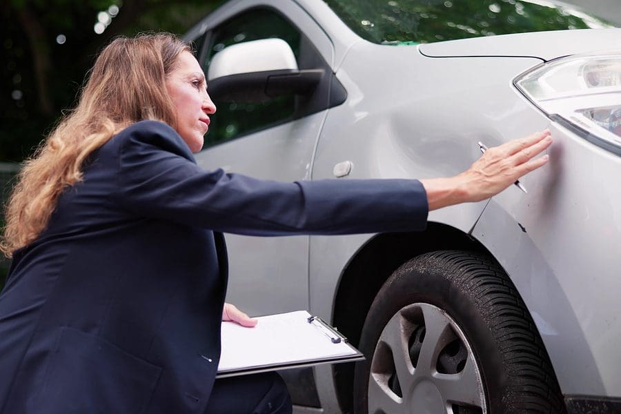 Insurance Agent Inspecting Damaged Car With Insurance Claim Form
