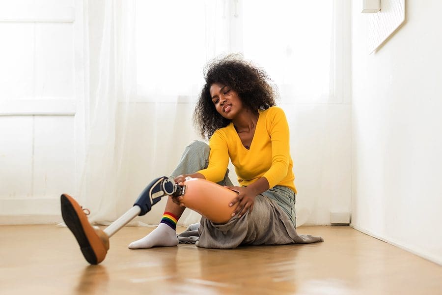 Image of a woman sitting on the floor trying to remove her artificial leg, example of damages with a long-term disability