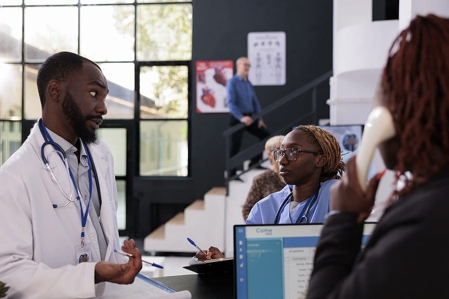 Practitioner Doctor Talking With Medical Assistant Discussing Pa