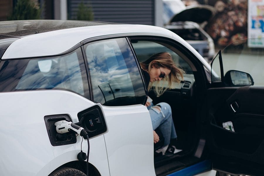 Woman charging electro car at the electric gas station