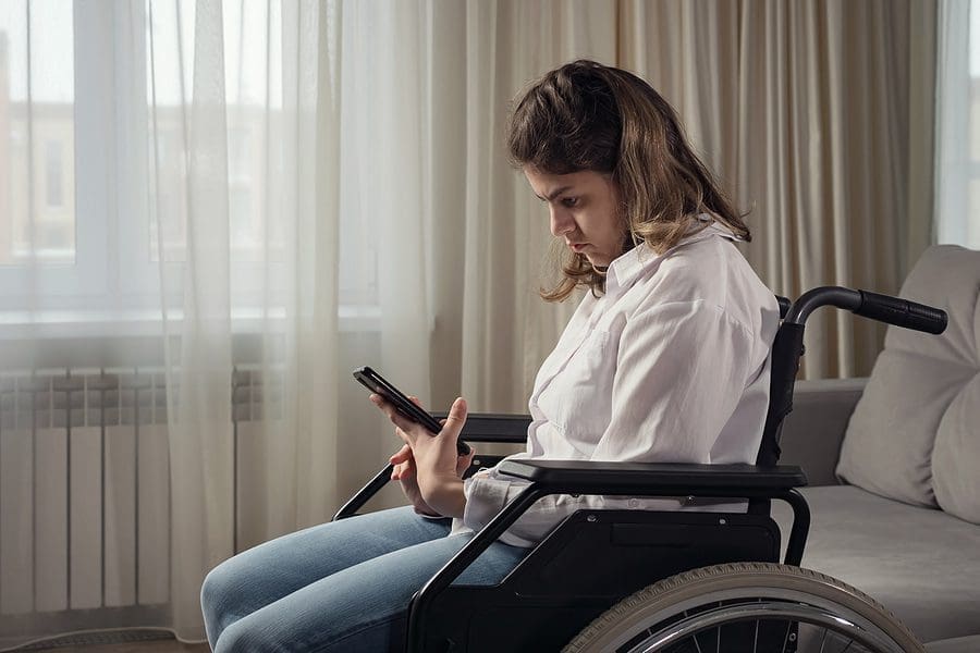 Young disabled woman with infantile cerebral paralysis tries to read news in mobile phone