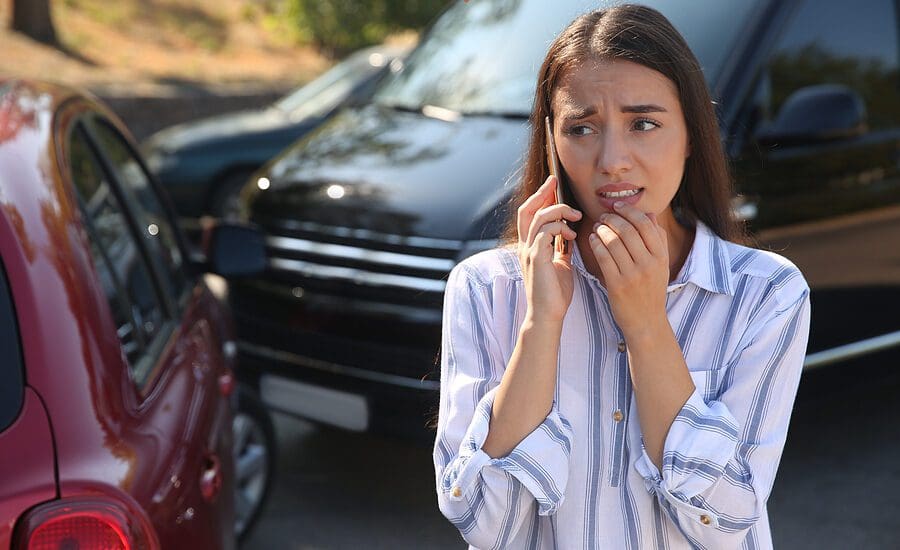 Woman talking on the phone at the the scene of a car accident looking stressed