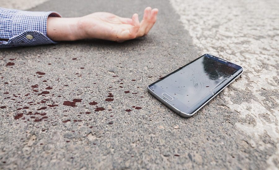 Pedestrian laying injured in a crosswalk with their shattered phone after a driver failed to yield right of way