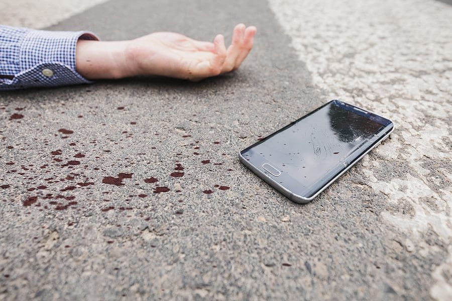 Pedestrian laying injured in a crosswalk with their shattered phone after a driver failed to yield right of way