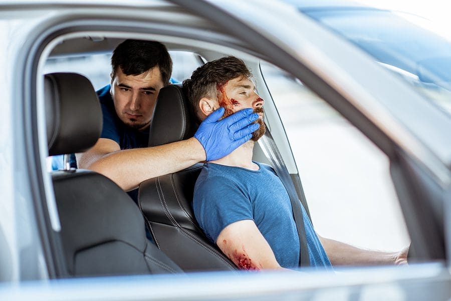 Driver with blunt force trauma head injury after a car accident being helped by a paramedic