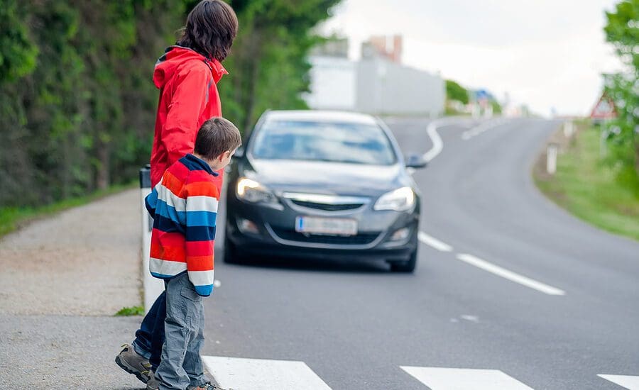 Mom and young son crossing the street while a car approaches