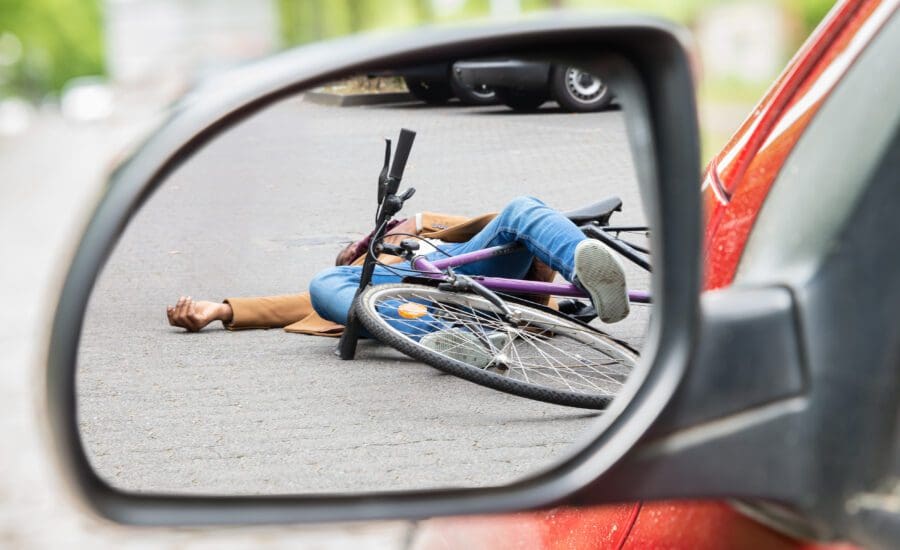 Bicyclist lying injured in the road after a bicycle accident with a car