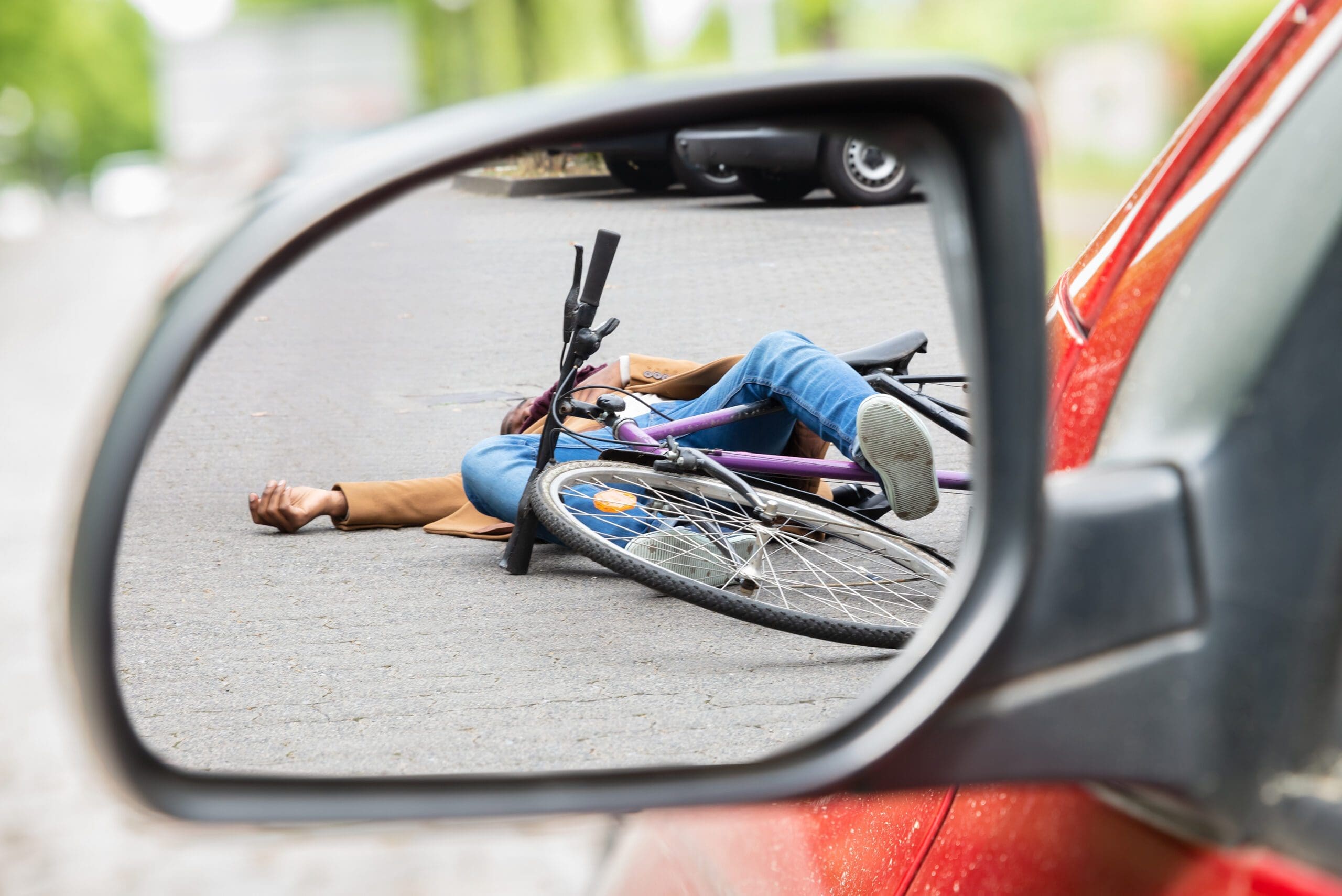 Bicyclist lying injured in the road after a bicycle accident with a car