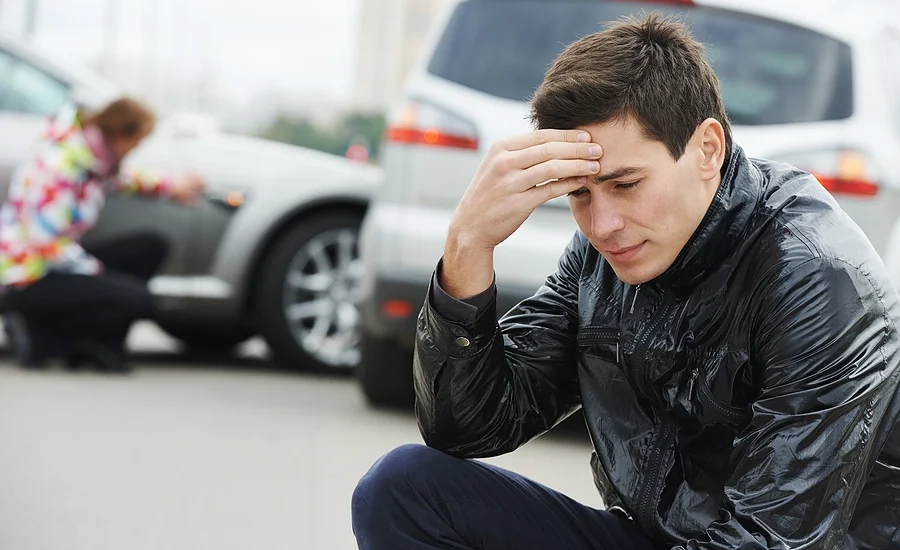 man with a head injury sitting on the curb upset after a Magnolia Heights car accident