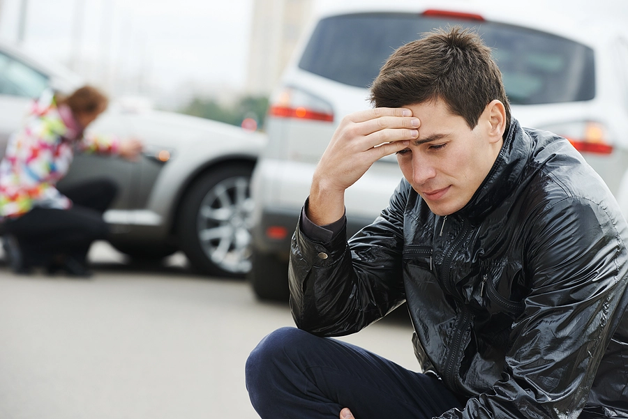 man with a head injury sitting on the curb upset after a Magnolia Heights car accident