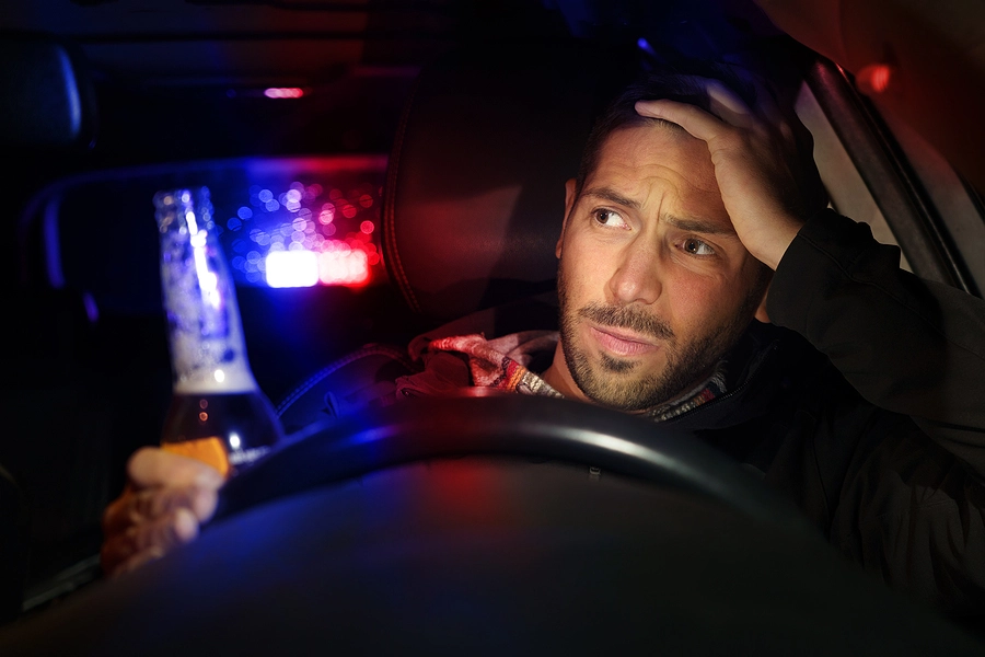 male drunk driver, which is more common according to statistics on DUIs, with a bottle in his hand getting pulled over by the police