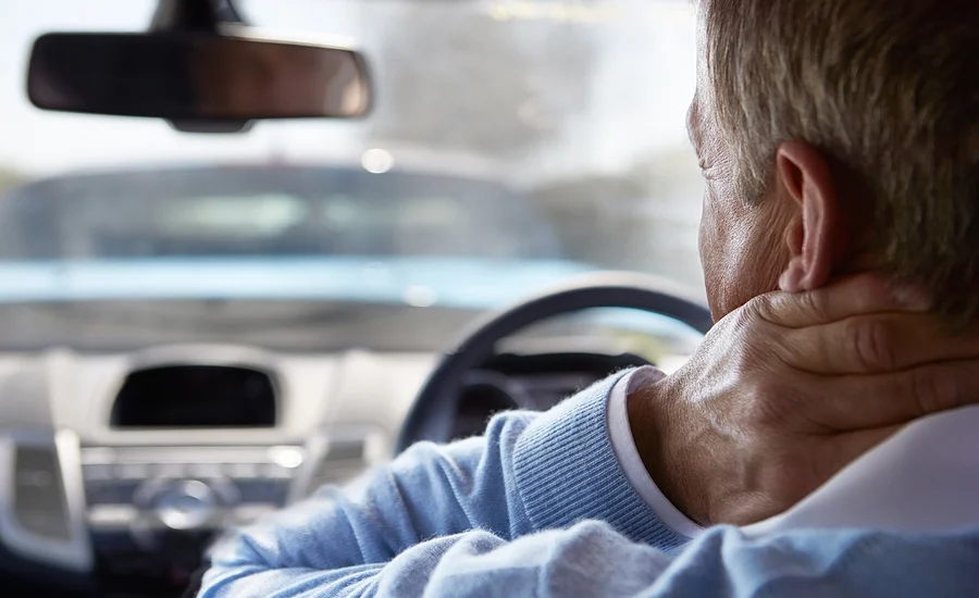 driver with whiplash holding his neck after a lakewood estates car accident