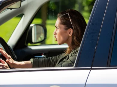 female driver engages in an example of risk while driving by honking her horn and tailgating