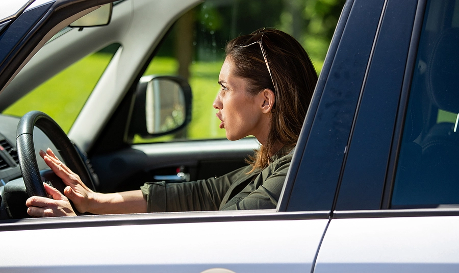 female driver engages in an example of risk while driving by honking her horn and tailgating