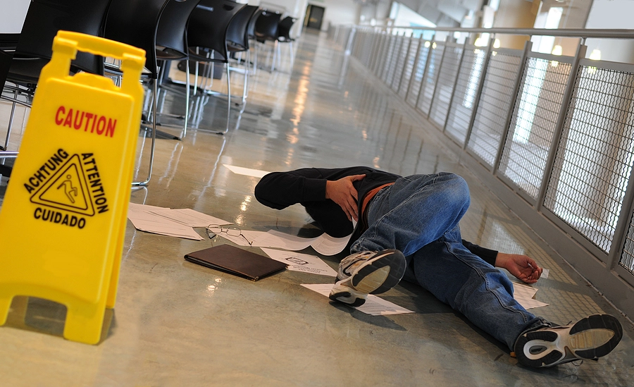 man with a leg injury laying on the floor with papers scattered around him after a slip and fall accident in a broadwater office building