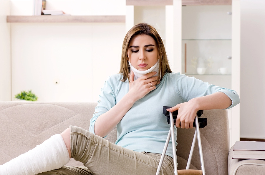 young kenneth city woman with crutches sitting on her couch recovering from a neck injury and a leg injury