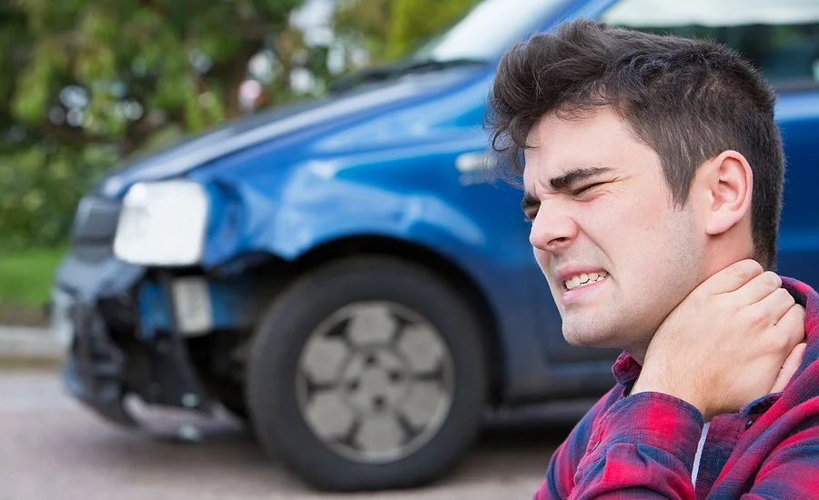 young kenneth city man holding his neck after a personal injury accident that damaged his car