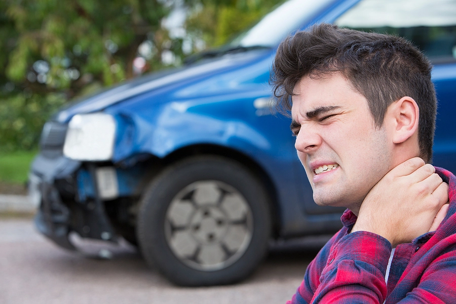 young kenneth city man holding his neck after a personal injury accident that damaged his car