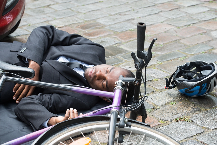 young black businessman laying on the ground injured next to his bicycle after being hit by a car in pinellas park