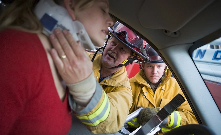 firefighters put a neck brace on an injured female driver after an edgemoor car accident