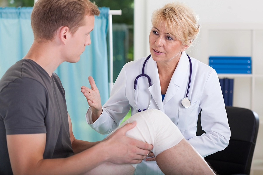 young man with an injured leg talks to a female doctor about medical treatment after an edgemoor personal injury accident