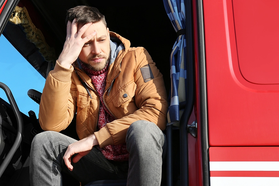 largo truck driver looking tired and holding his head, fatigue can lead to a truck accident