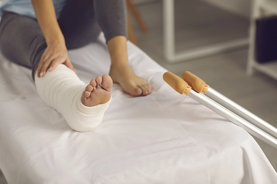 woman with crutches massages her leg in a cast after being injured in a madeira beach truck accident