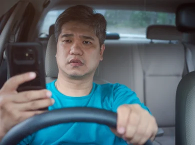 asian male driver texting while driving represents an example of negligence in an automobile accident