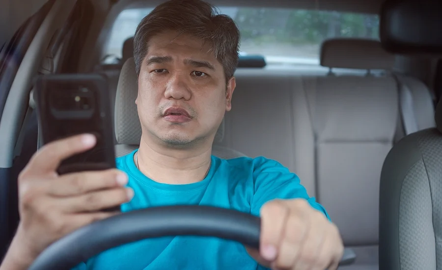 asian male driver texting while driving represents an example of negligence in an automobile accident